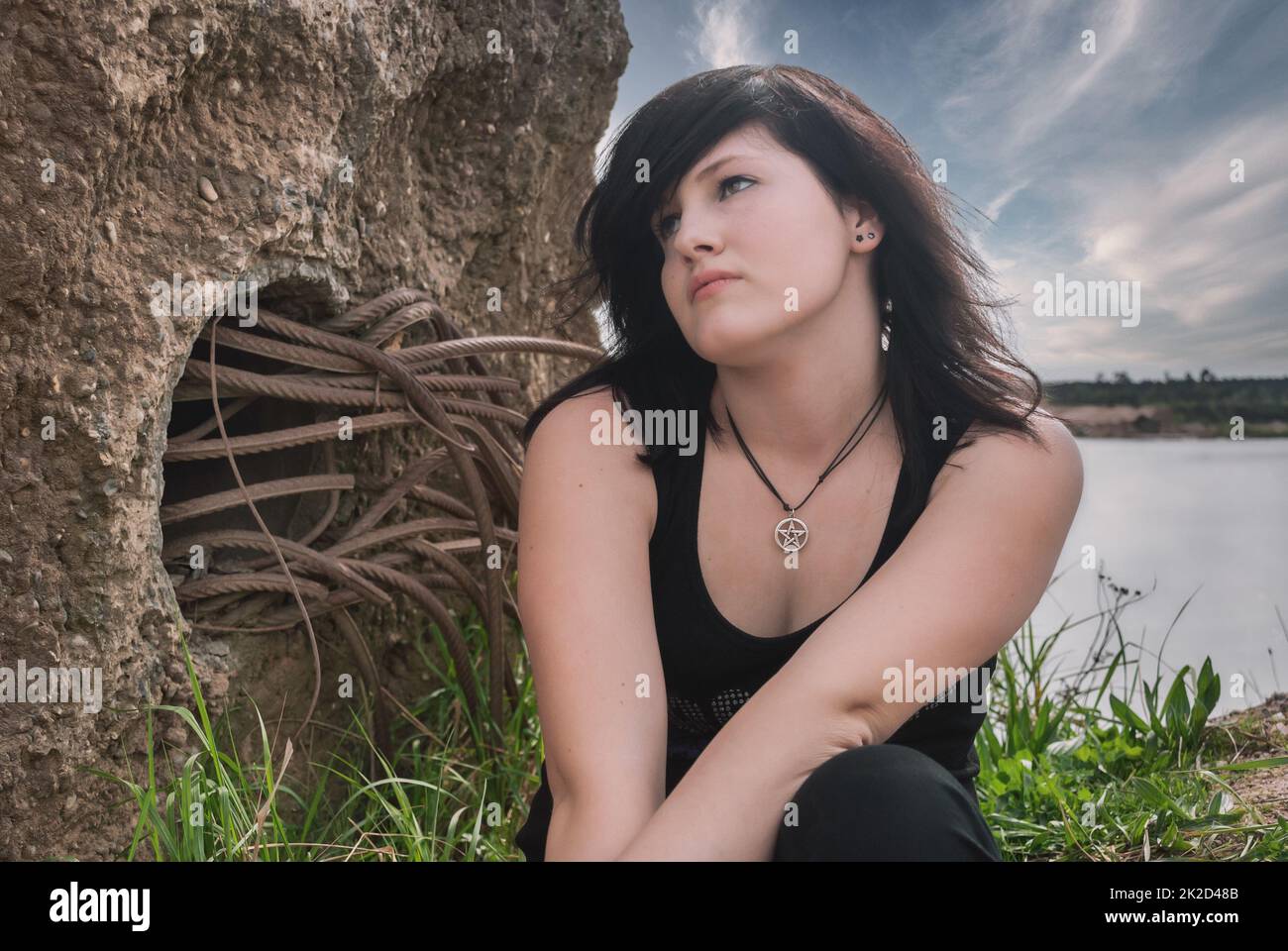 Donna punk emogotica seduta al lago Foto Stock