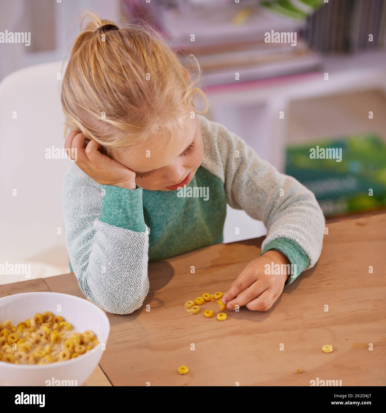 Non mi piace questo cereale. Scatto di una ragazza piccola che osserva triste mentre mangiano la colazione a casa. Foto Stock