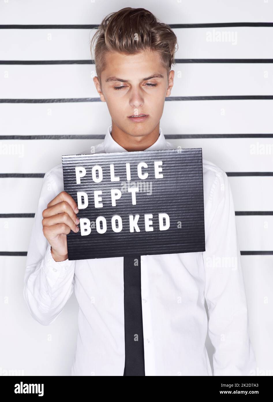 Sentire le conseguenze. Tazza di un giovane uomo in una camicia e cravatta tenendo un cartello del dipartimento della polizia. Foto Stock