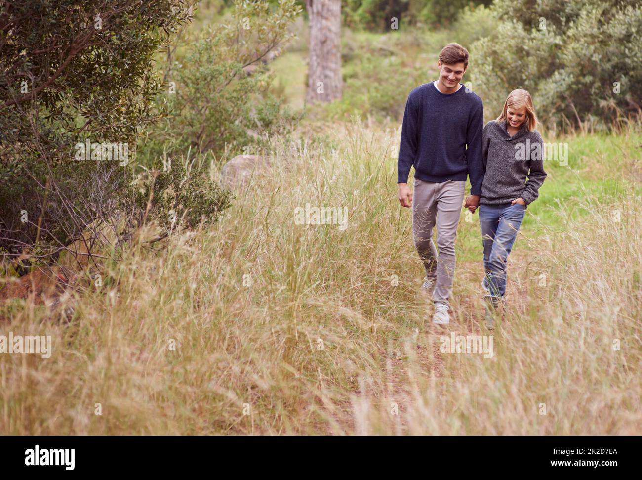 Passeggiata in campagna. Una giovane coppia passeggiando a mano attraverso un prato. Foto Stock