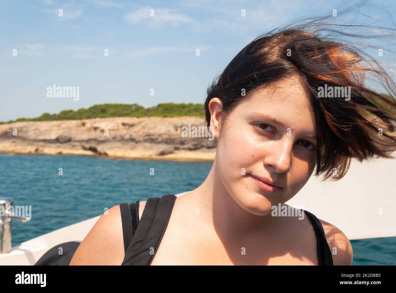 Donna con capelli neri arancioni che guarda la macchina fotografica, in piedi su una nave Foto Stock