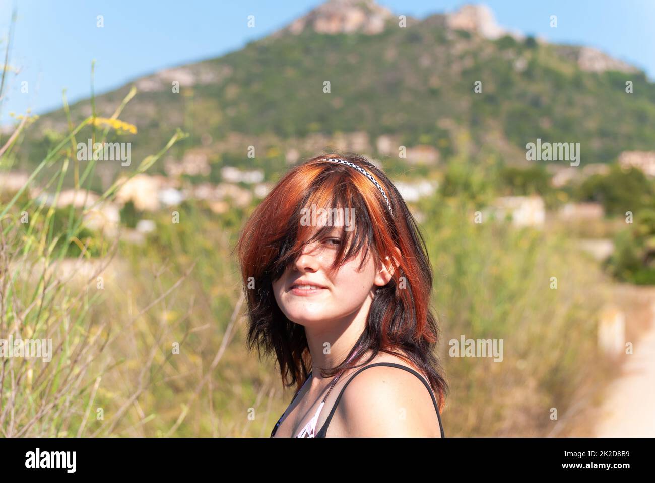 Giovane donna con capelli neri arancioni che guarda la macchina fotografica, maiorca Foto Stock