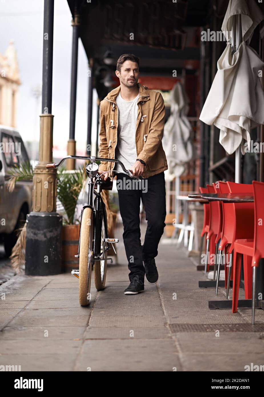 Il suo tempo di ciclo. Scatto di un giovane uomo alla moda che spinge la bicicletta sul marciapiede. Foto Stock