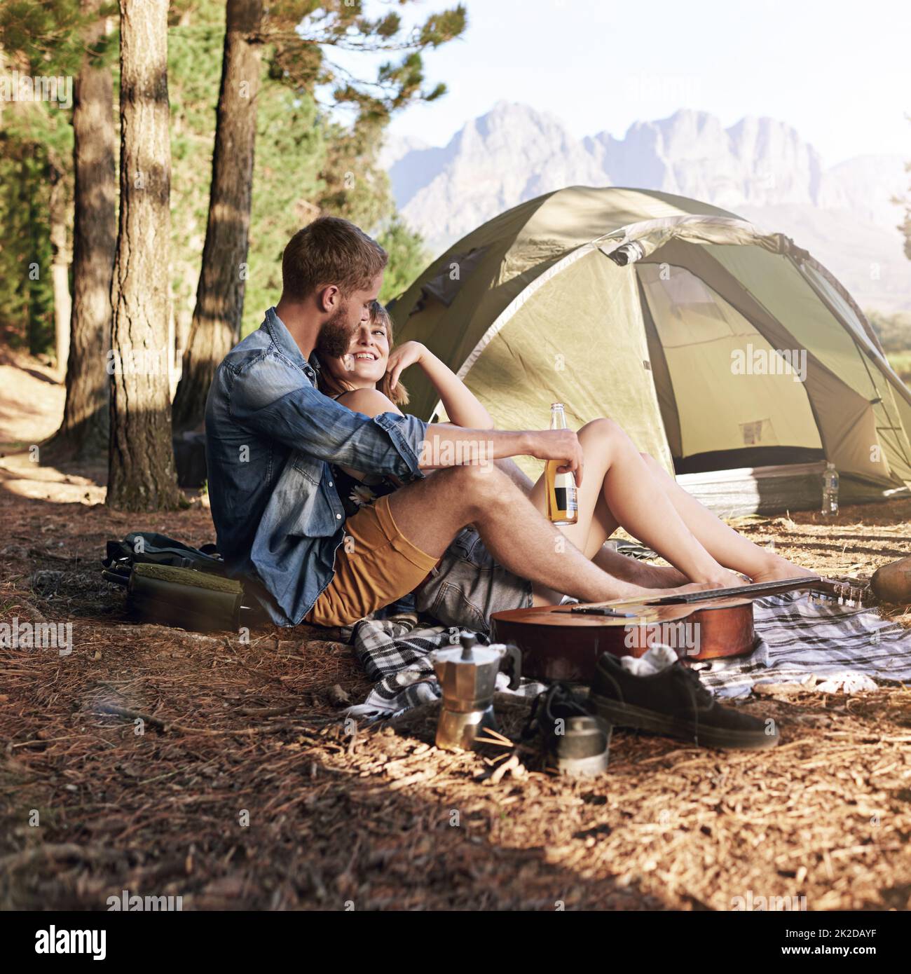 Nei boschi. Scatto di una giovane coppia affettuosa seduta al loro campeggio. Foto Stock