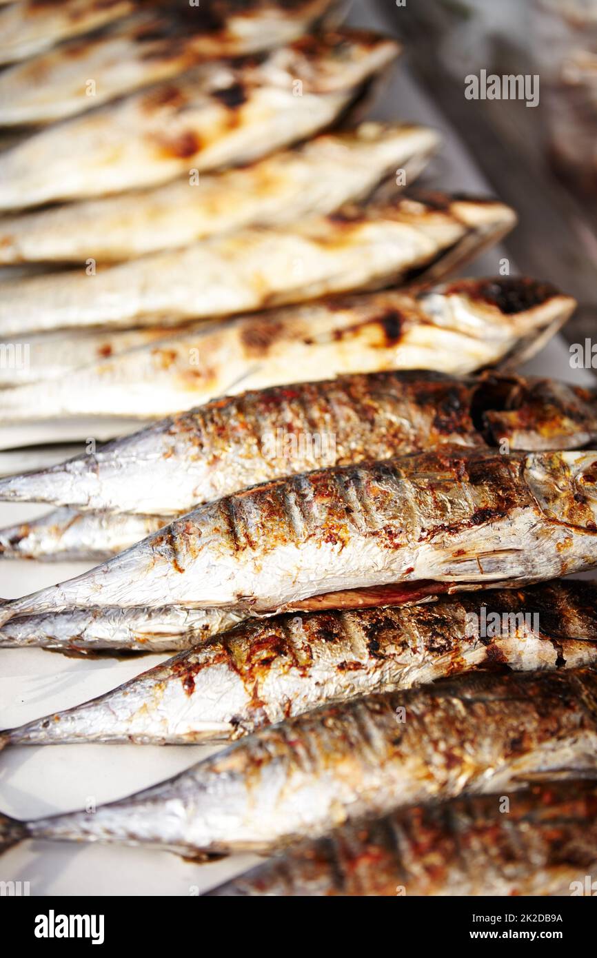 Confezionate come sardine. Primo piano di sardine cotte in fila pronte per mangiare in una bancarella del mercato thailandese. Foto Stock