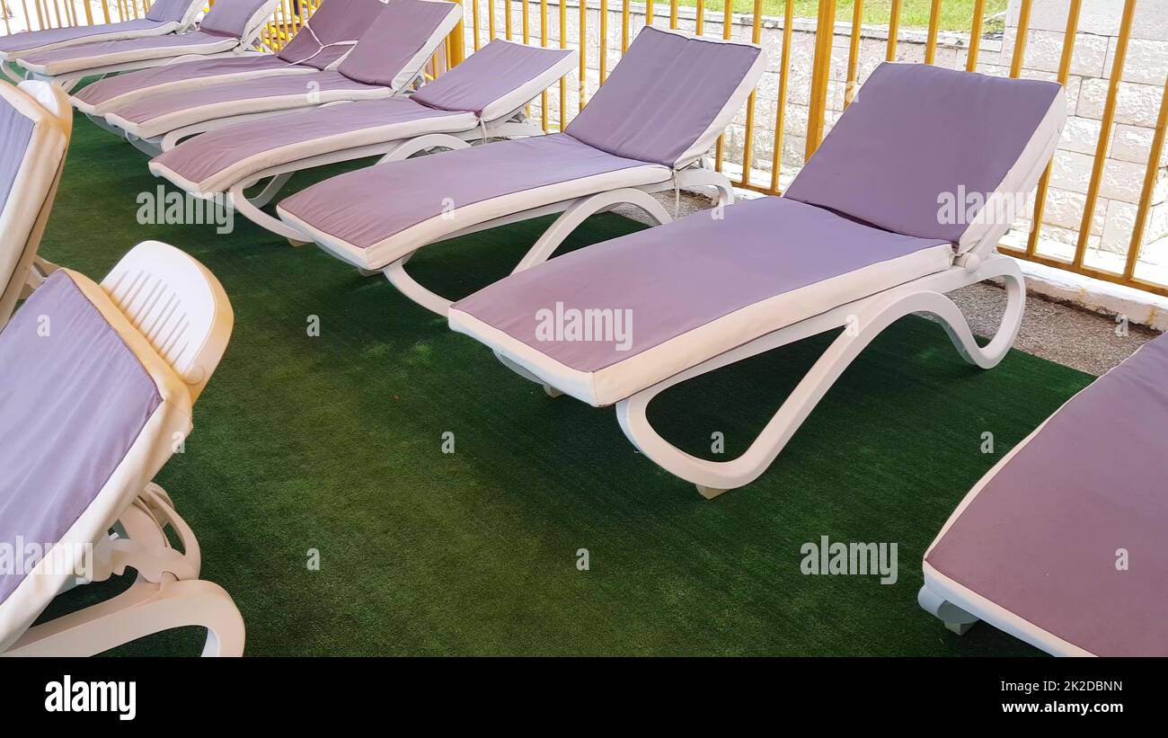 sedie a sdraio vuote si trovano in fila sotto il tetto del solarium per prendere i bagni d'aria sulla riva del mare, una località turistica Foto Stock