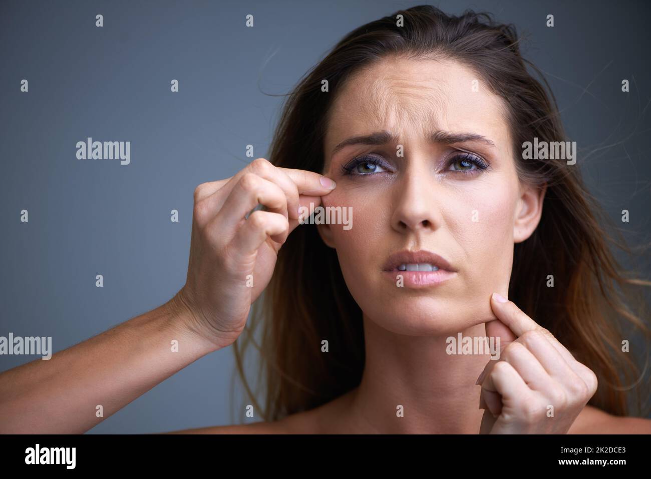 Questo trattamento cutaneo NON funziona. Una giovane donna attraente che osserva delusa mentre tira sulla sua pelle. Foto Stock
