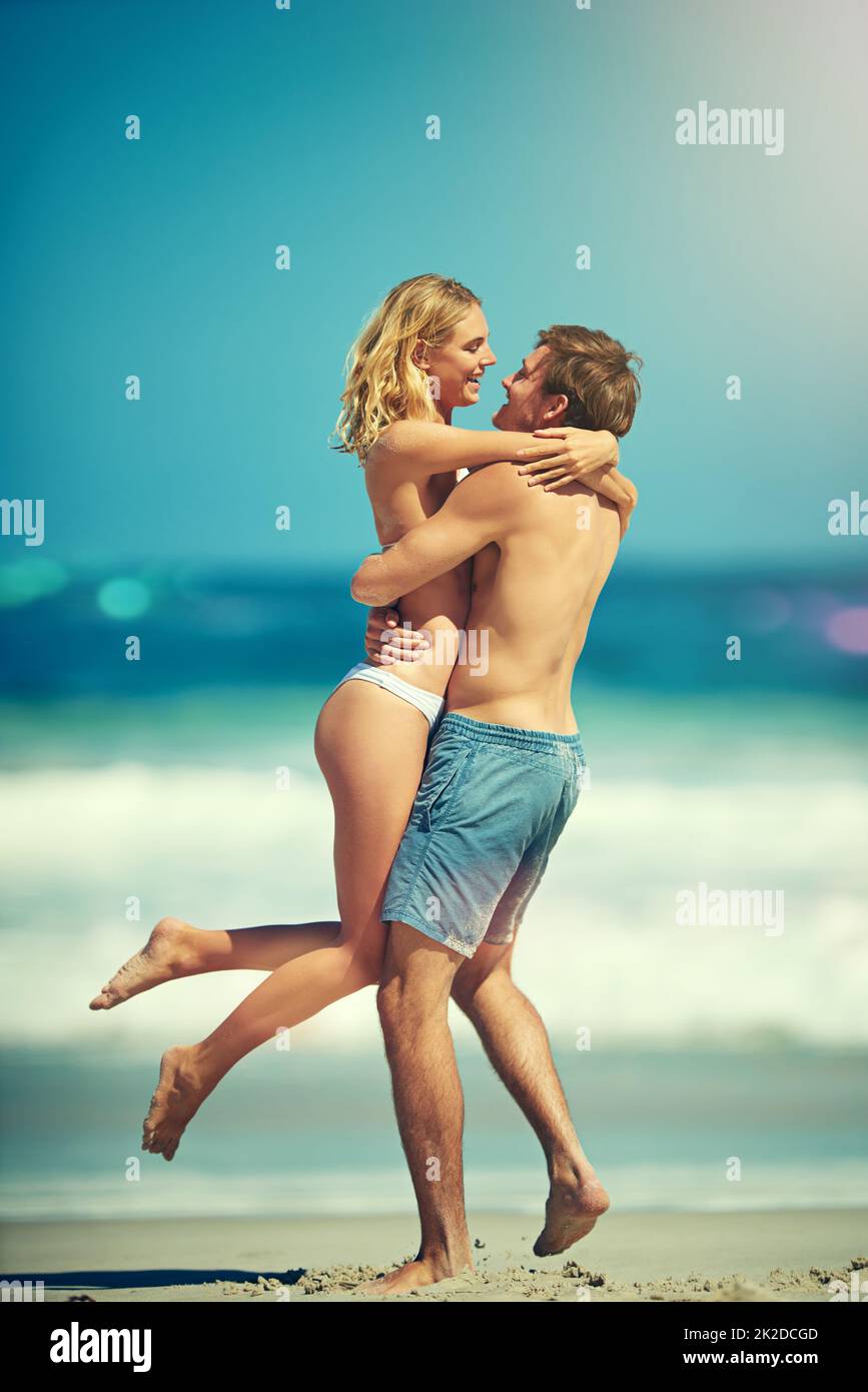Tieni l'amore vicino. Scatto a tutta lunghezza di una giovane coppia affettuosa che si abbraccia sulla spiaggia. Foto Stock