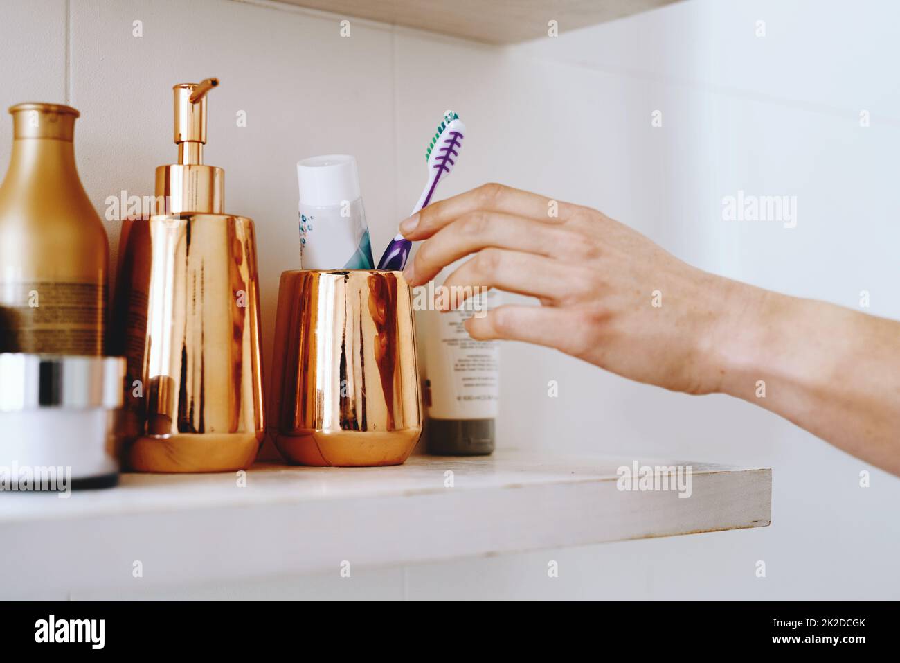 Iniziate la giornata con un po' di freschezza. Scatto corto di una donna irriconoscibile che tira fuori uno spazzolino dal suo armadietto del bagno. Foto Stock