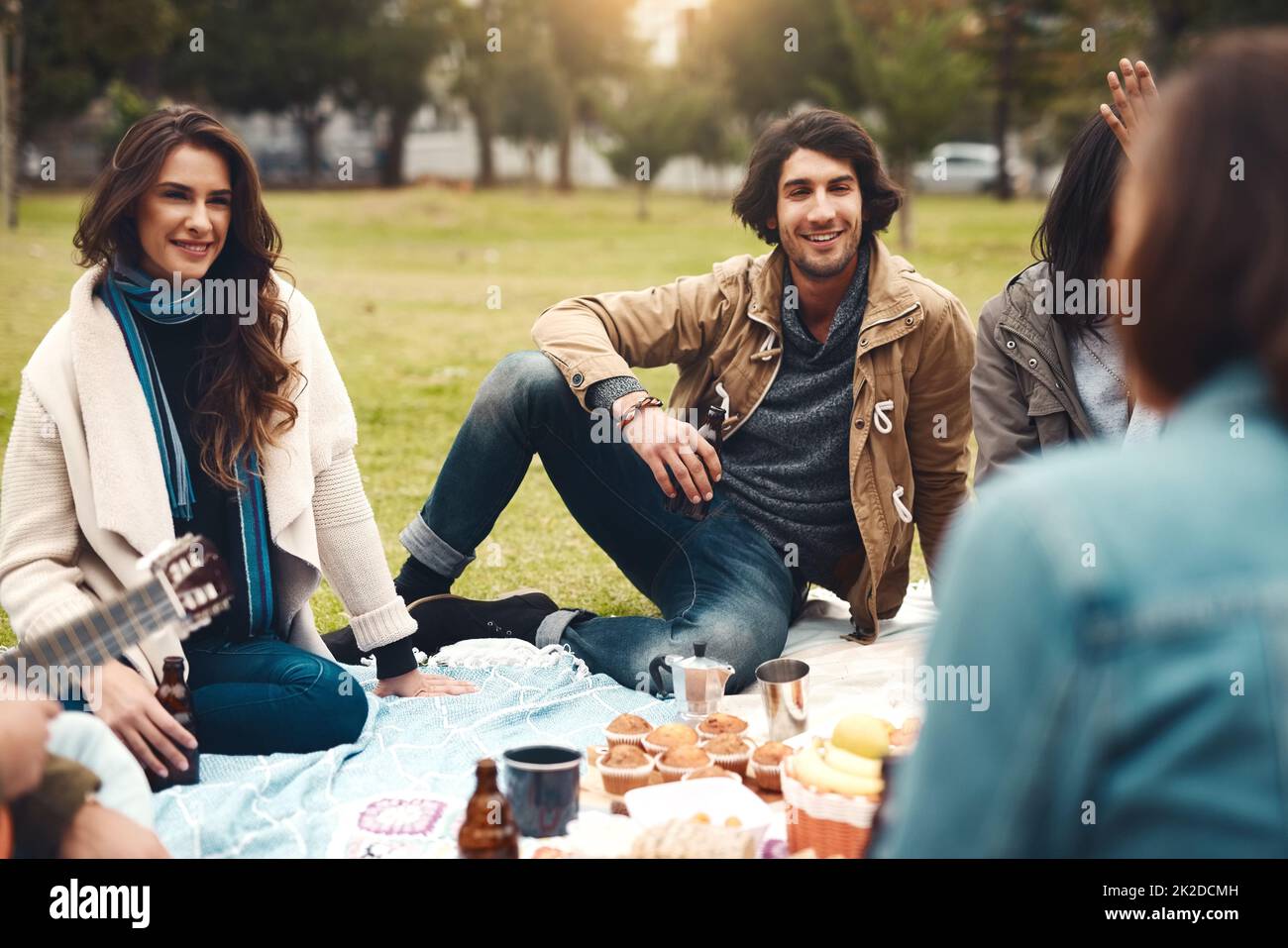 Sembra che siano stati ordinati con spuntini. Shot di un gruppo di giovani amici allegri che hanno un picnic insieme fuori in un parco durante il giorno. Foto Stock