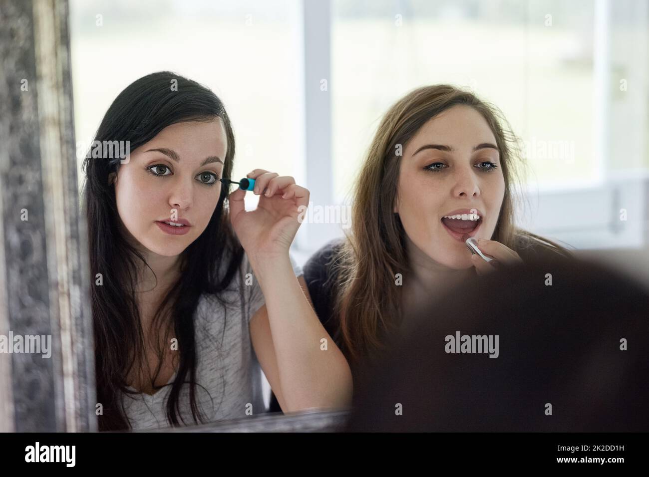 Solo un paio di acrobazie. Scatto corto di due giovani amiche che mettono sul trucco in bagno. Foto Stock