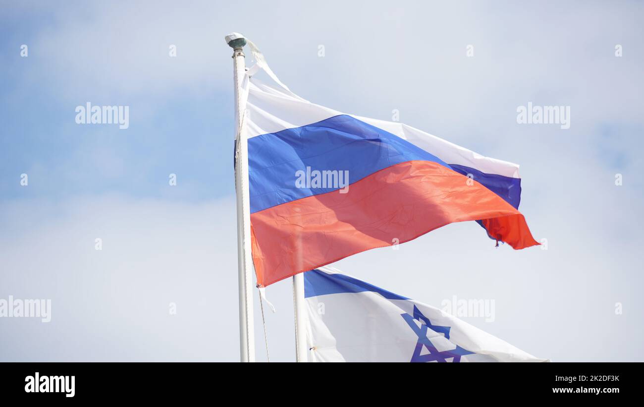 Le bandiere russe e israeliane si intrecciano nel vento contro cieli luminosi Foto Stock