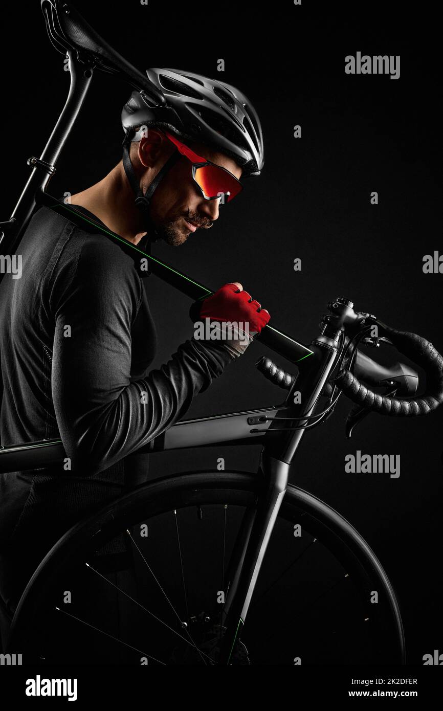 ciclista maschile con bicicletta da strada su sfondo nero Foto Stock