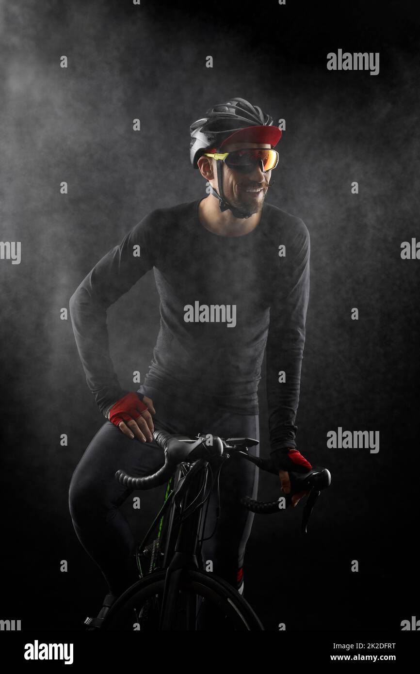 ciclista maschile con bicicletta da strada su sfondo nero Foto Stock