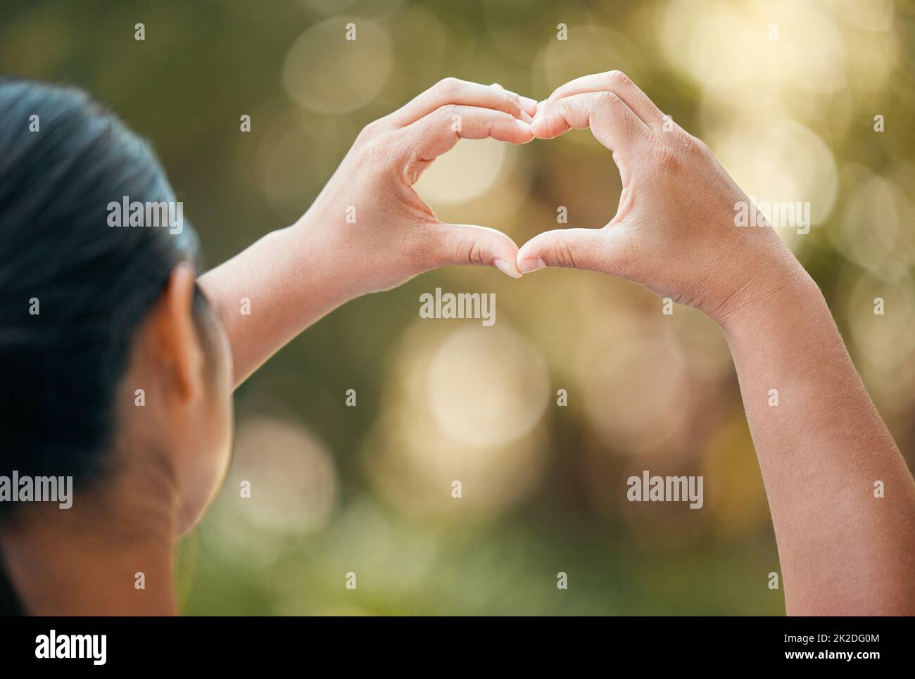 Donna usare le mani, fare il cuore o segno d'amore fuori con bokeh in sfondo naturale. Donna con le dita insieme, mostra icona o espressione di romanticismo Foto Stock