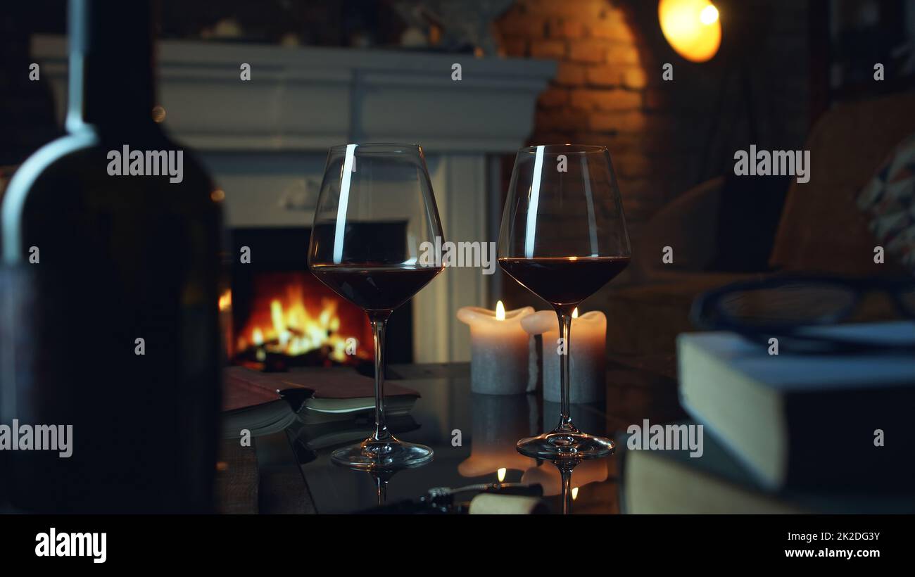 Vino, libro e camino a casa in inverno Foto Stock