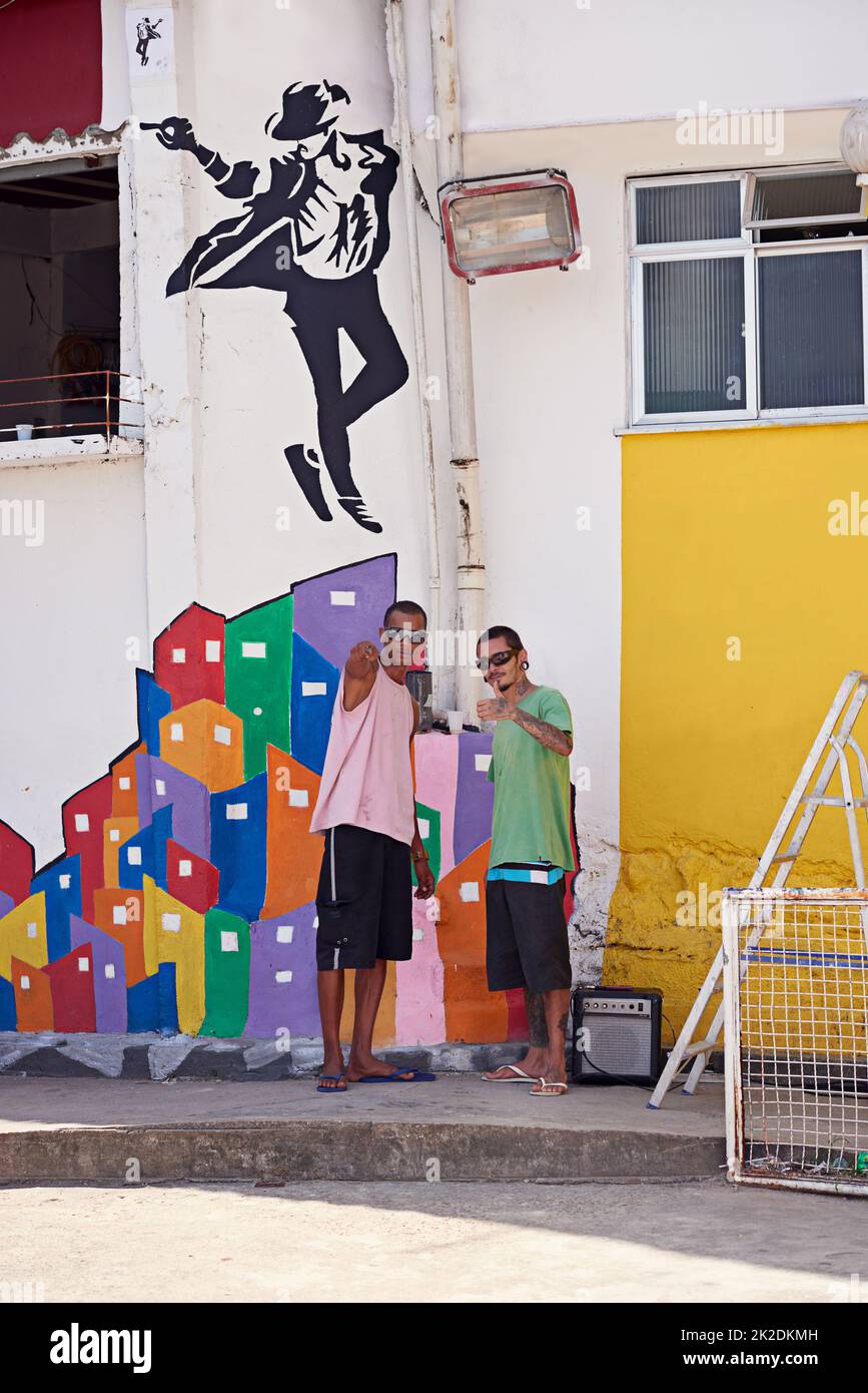 Due giovani graffiti in piedi accanto alla loro arte murale Foto Stock