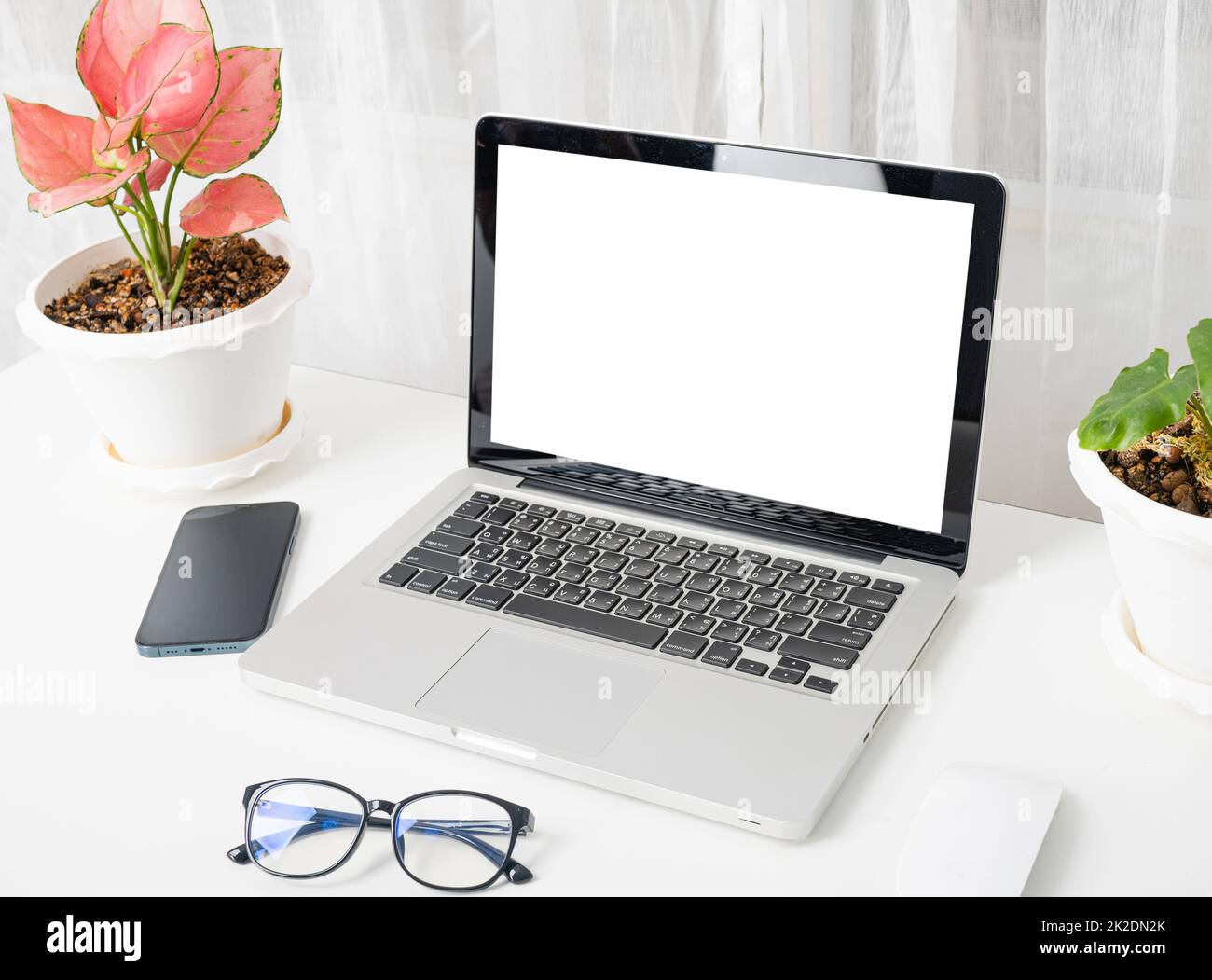 computer portatile mock up schermo bianco vuoto, occhiali e smartphone tavolo bianco Foto Stock