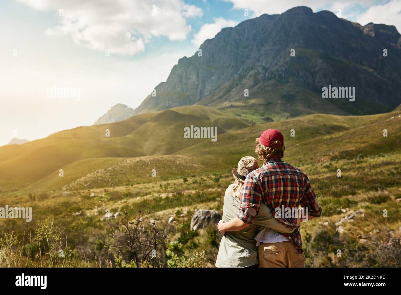 Hanno trovato il loro posto nel mondo. Foto retrostenibile di una giovane coppia ammirando una vista montagnosa nella natura. Foto Stock