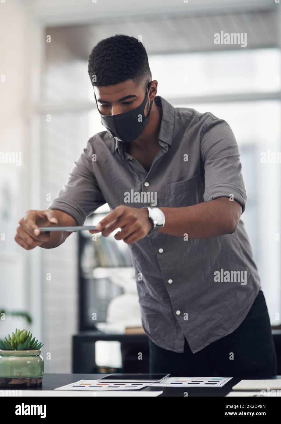 Scattare foto per aiutarlo a vedere il quadro più grande. Scatto di un giovane designer che scatta foto del suo lavoro in un ufficio. Foto Stock