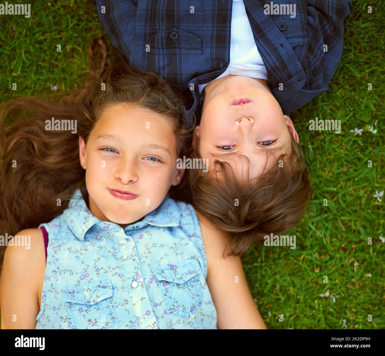 Trattenere il respiro. Colpo ad angolo alto di un fratello e di una sorella giovani che trattengono il respiro mentre si trovano sull'erba all'esterno. Foto Stock