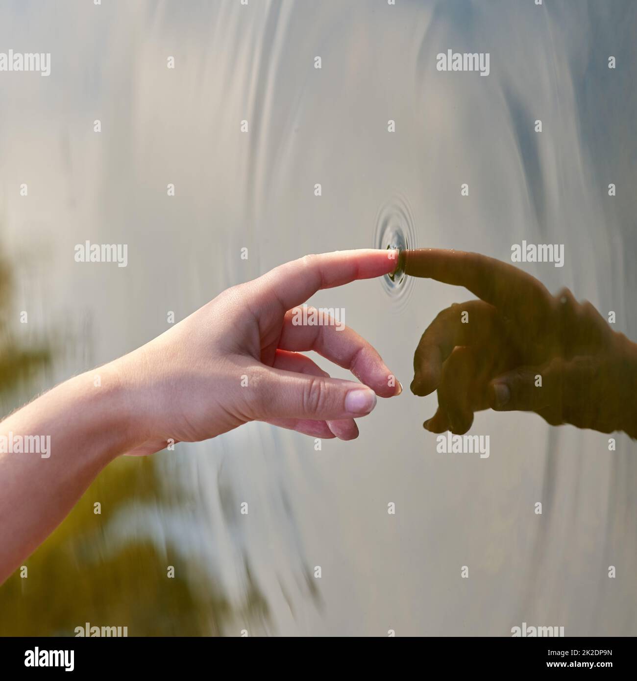 L'effetto ondulazione. Scatto ritagliato di un dito che tocca l'acqua per formare increspature. Foto Stock