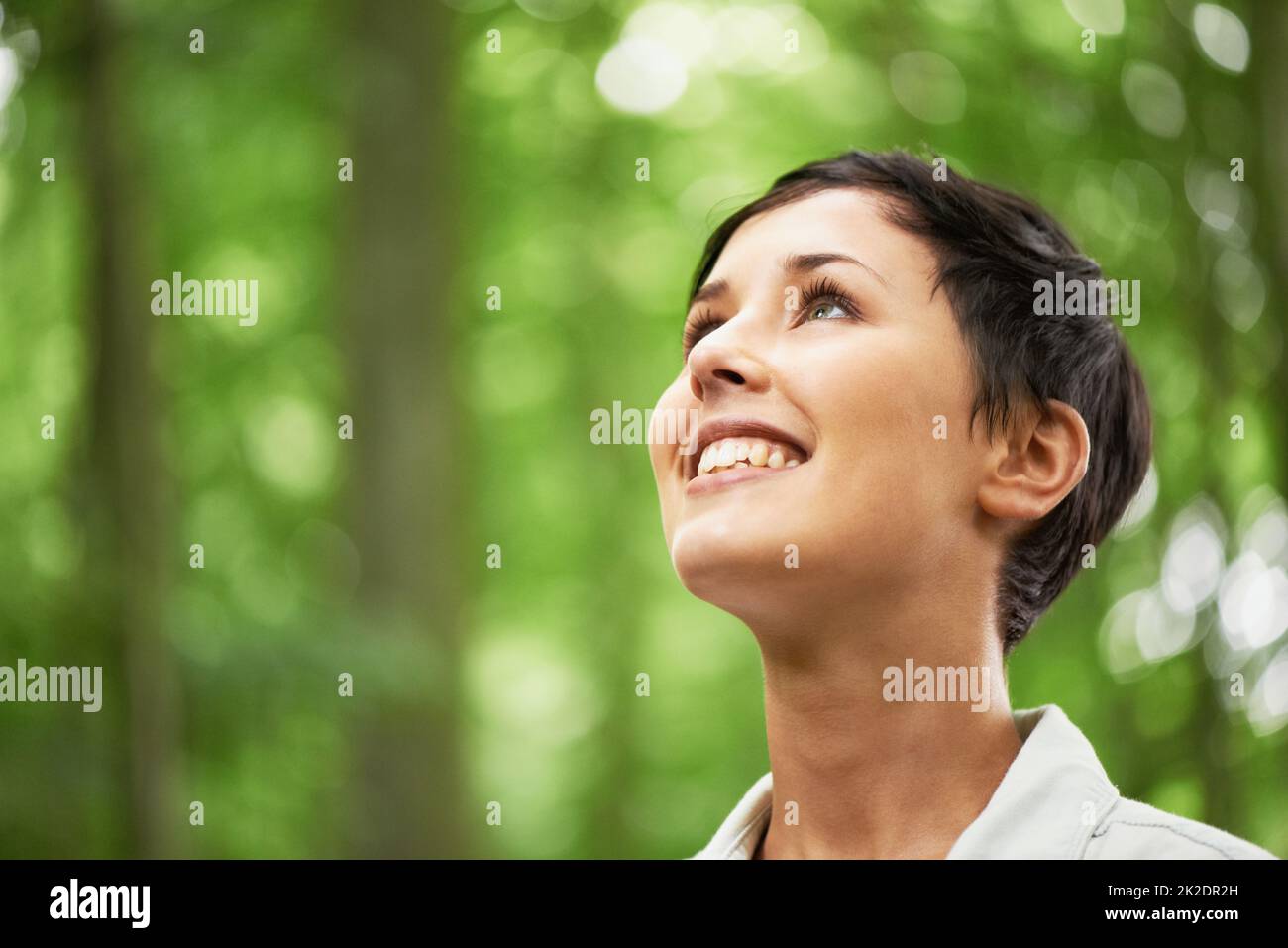 Un amore per tutte le cose nella natura. Un primo colpo di una giovane donna attraente che guarda verso l'alto nella baldacchino di una foresta. Foto Stock