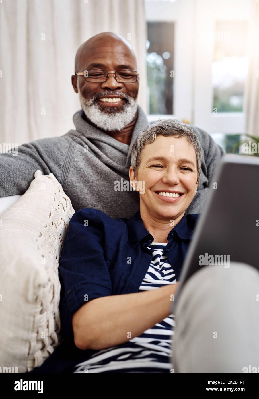 Abbiamo trascorso un fine settimana meraviglioso al coperto. Scatto di una coppia anziana affettuosa usando un tablet mentre si rilassa sul divano a casa. Foto Stock
