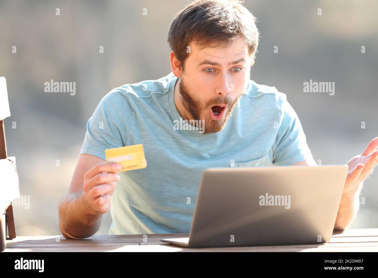 Stupito uomo che acquista online con un computer portatile e una carta di credito Foto Stock