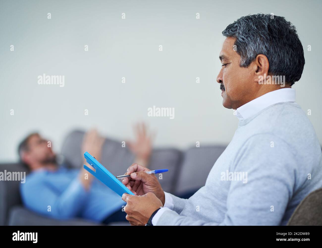 Parlare è la migliore terapia. Shot di un terapista che prende appunti durante l'ascolto di un paziente durante una sessione di consulenza. Foto Stock