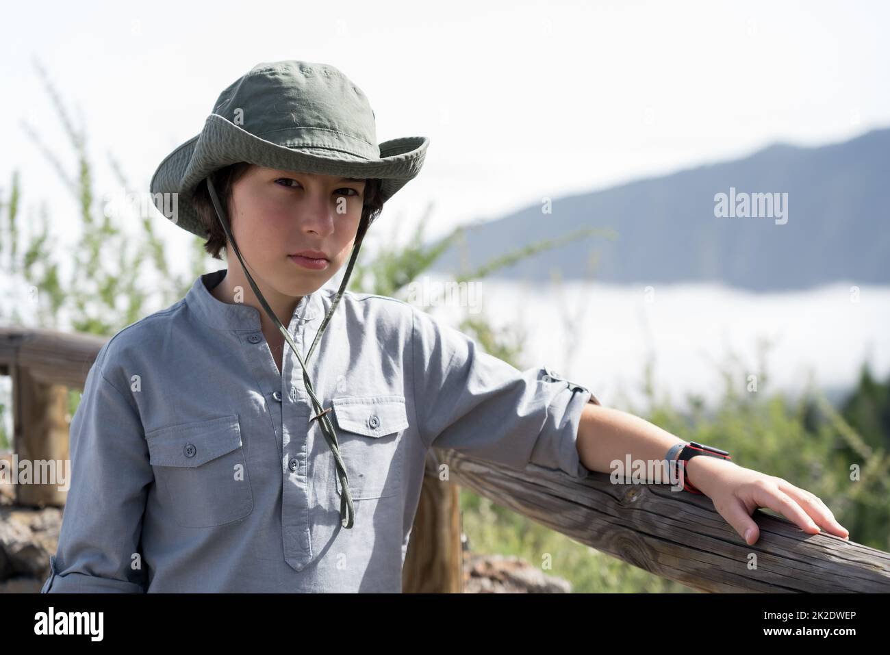 Un adolescente triste si erge su una piattaforma di osservazione in cima alle montagne. Foto Stock