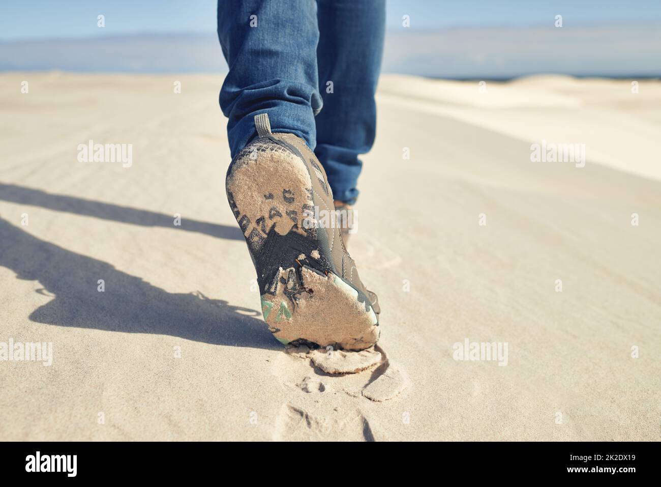 Nessun clima è troppo. Shot di un giovane escursionista maschile che cammina lungo le dune di sabbia. Foto Stock