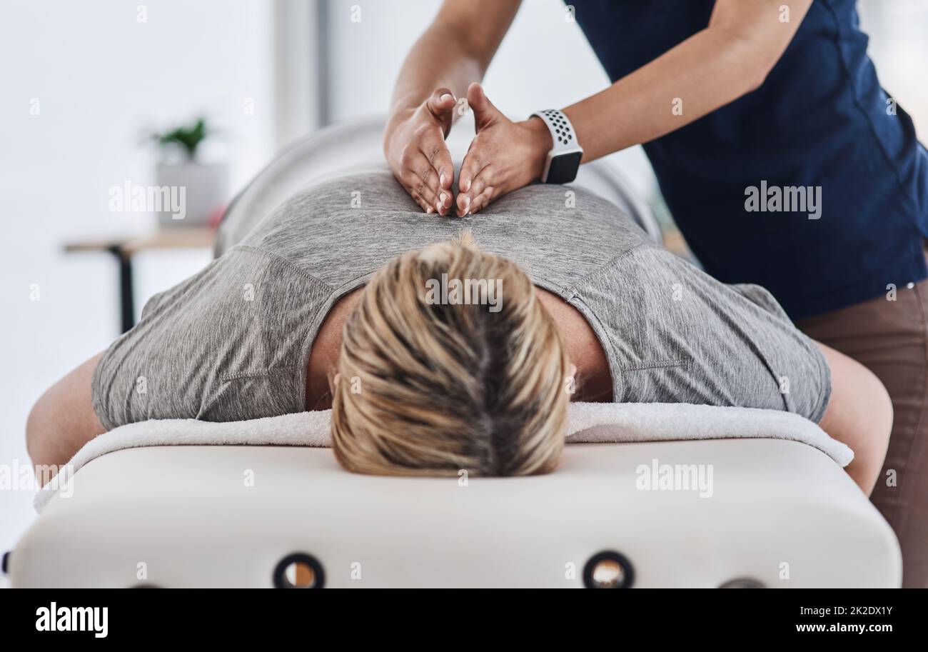La schiena ha bisogno di tutto il sollievo che può ottenere. Shot di una donna matura sdraiata faccia in giù e la schiena massaggiata da un fisioterapista in una clinica. Foto Stock