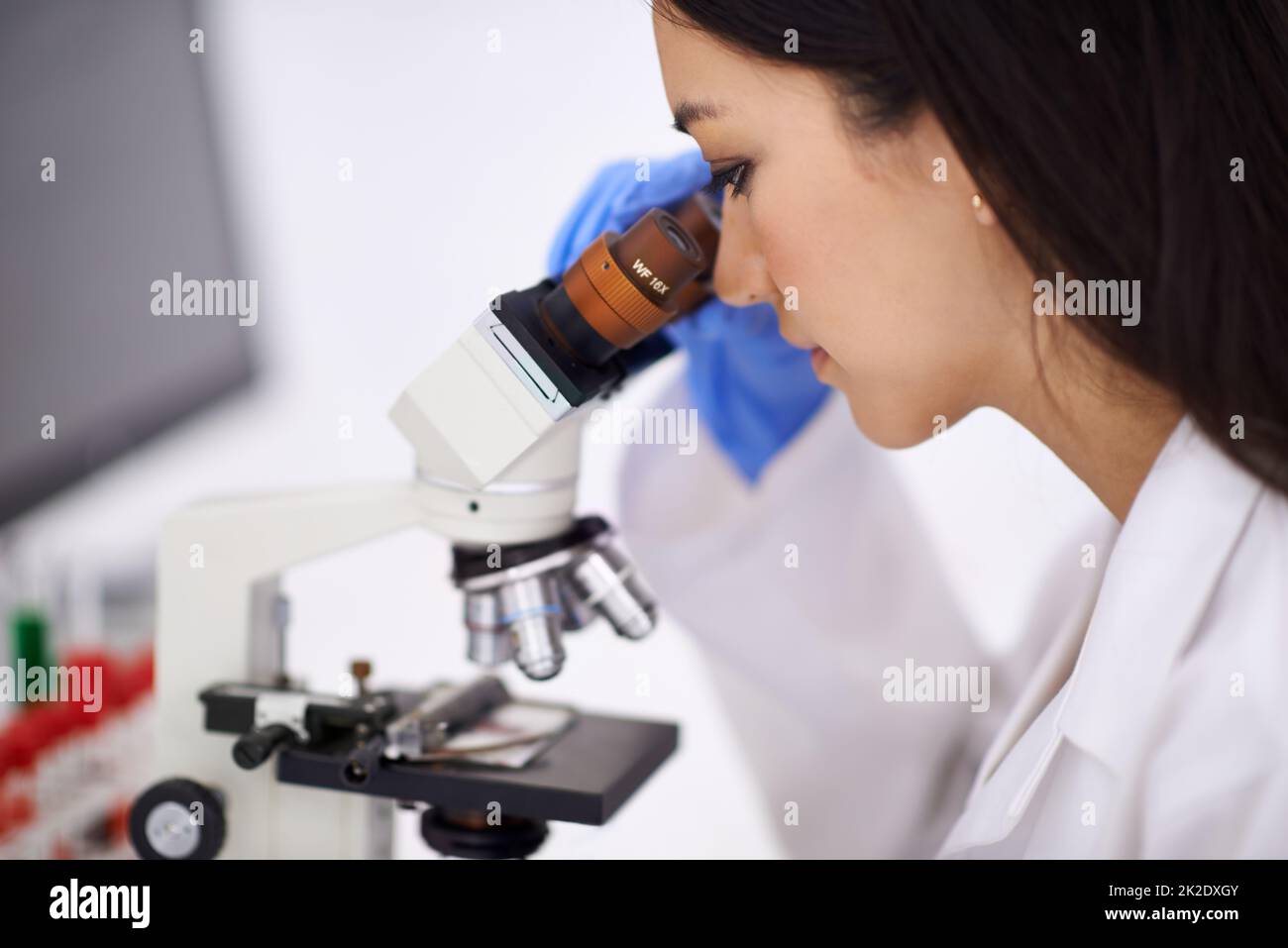 Shes un professionista a sangue-lavoro. Profilo di una scienziata femminile che guarda un campione al microscopio. Foto Stock