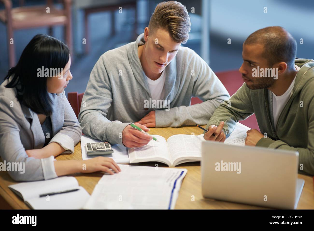Cramming alcune conoscenze dell'ultimo minuto. Un gruppo di giovani che studiano insieme nella biblioteca. Foto Stock