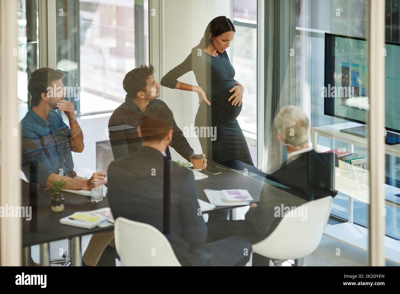 Tutti si preoccupano per lei. Colpo di una donna d'affari incinta in disagio durante una riunione. Foto Stock