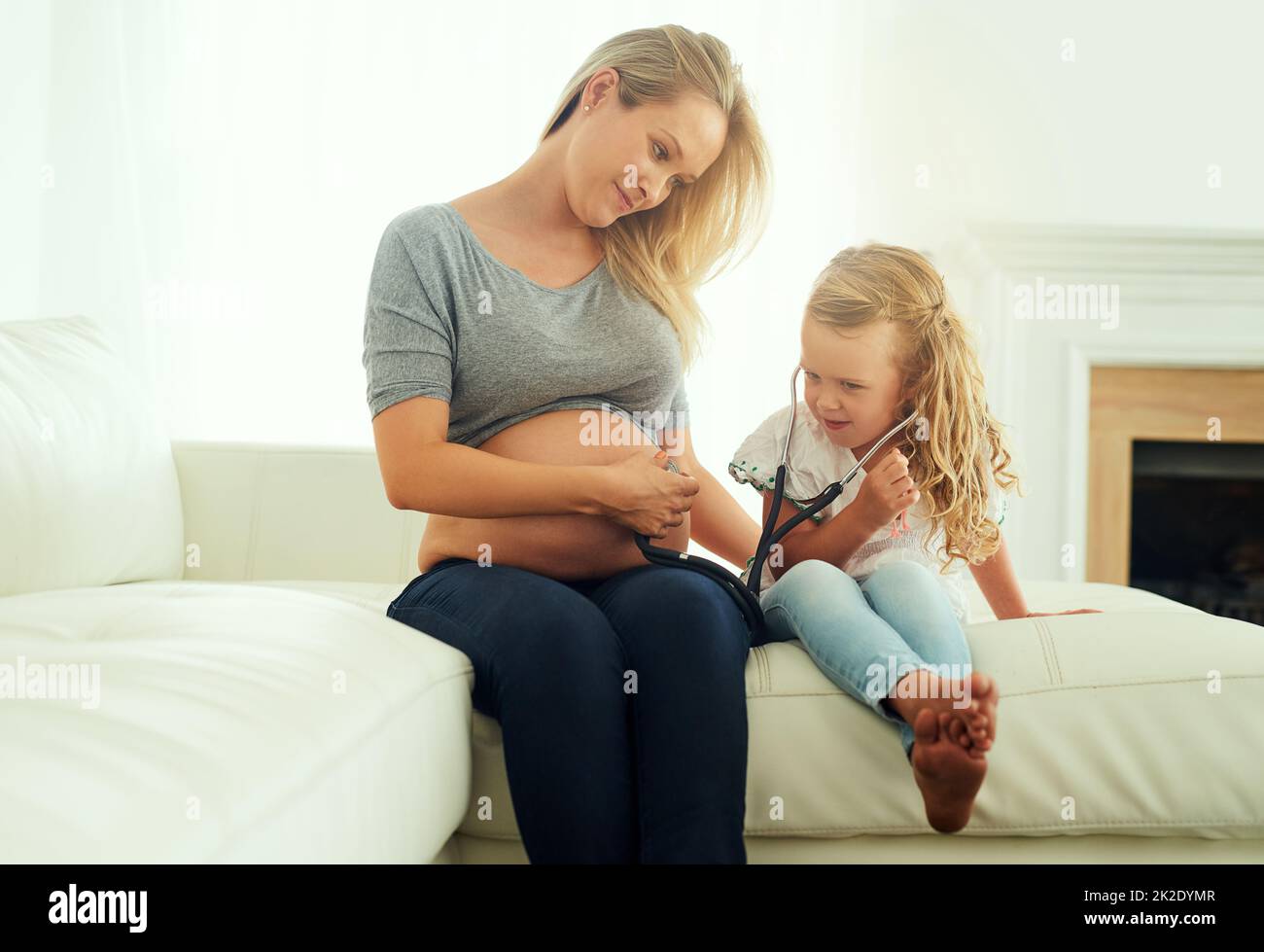 Legame con il suo fratellino. Scatto di una bambina usando uno stetoscopio per ascoltare le sue madri ventre incinta. Foto Stock