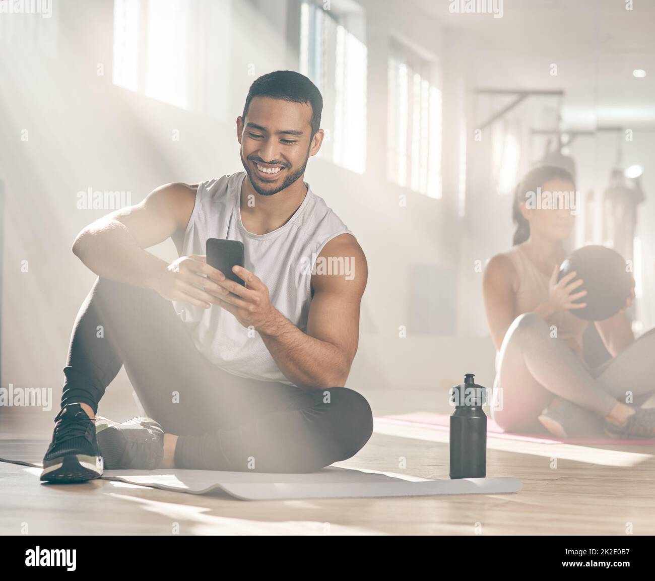 Questa app mi aiuta a restare in linea con i miei obiettivi di fitness. Scatto di un uomo che usa il suo cellulare mentre si fa una pausa in palestra. Foto Stock