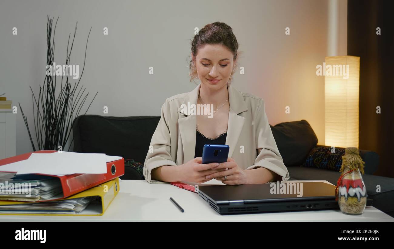 Donna che utilizza lo smartphone dopo una giornata di lavoro di successo. Foto Stock