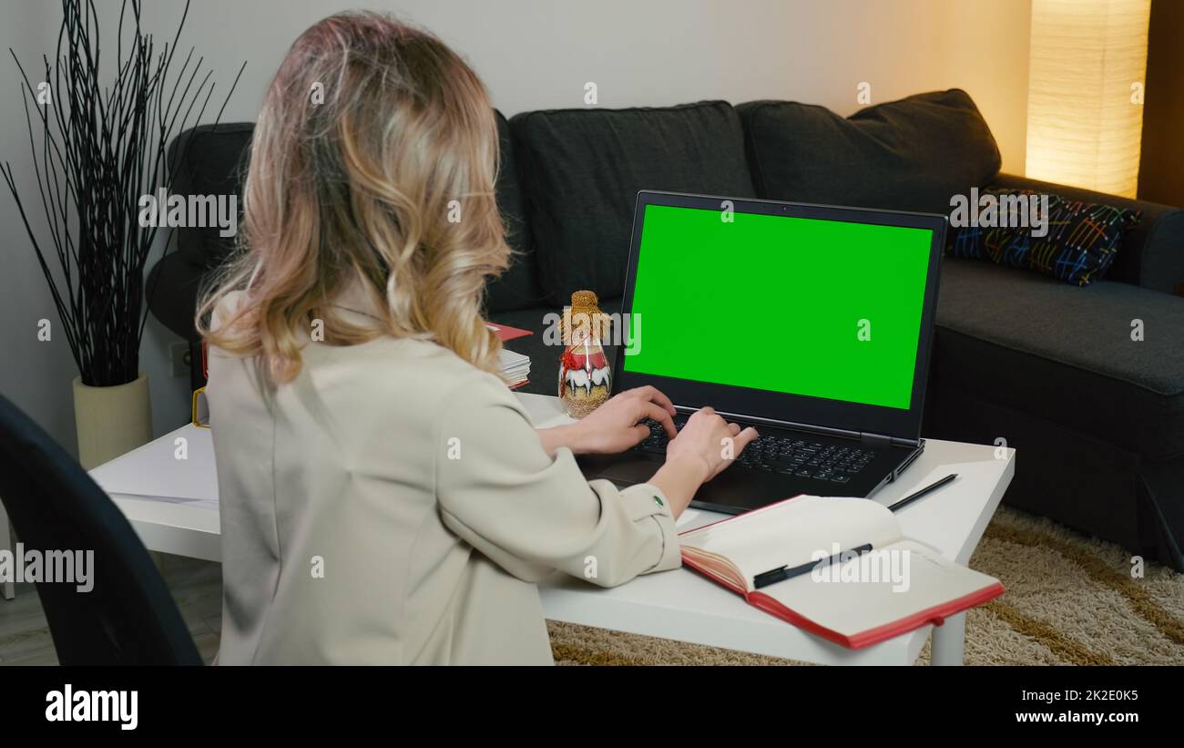 Donna di affari bionda seduta con la schiena nella giacca grigia digitando sul computer Foto Stock