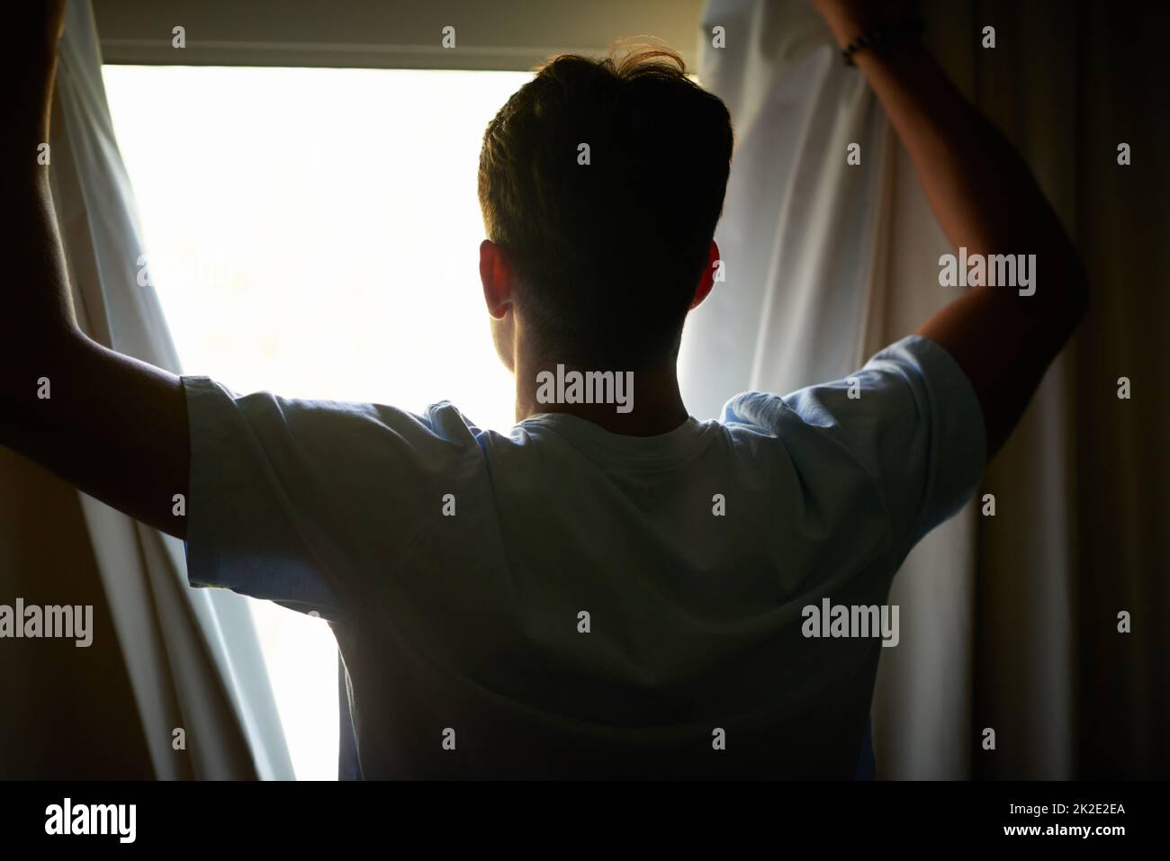 Il suo tempo di affrontare il mondo. Scatto retroguarda di un uomo che apre le sue tende per guardare la vista all'esterno. Foto Stock