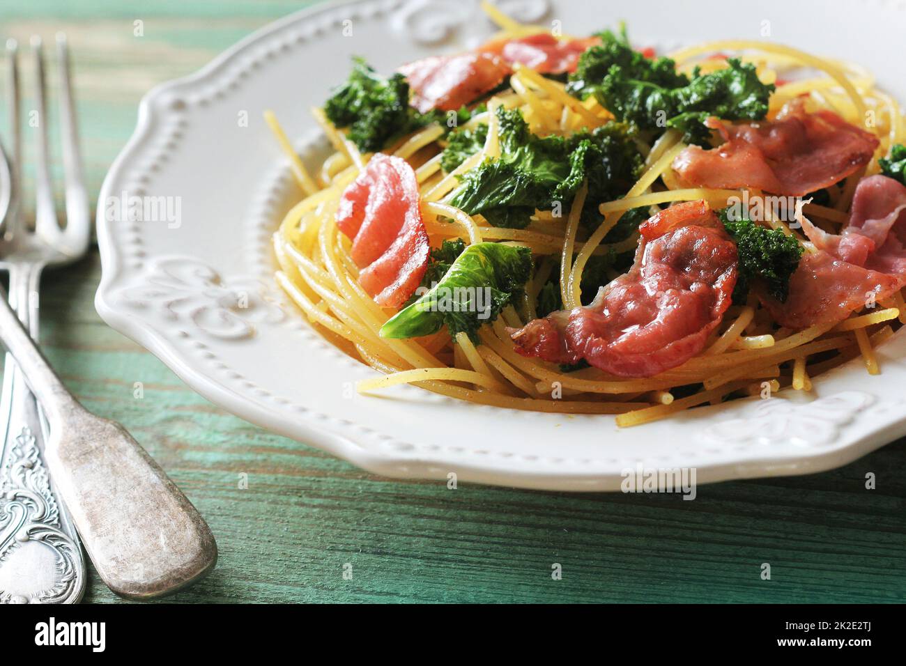 Deliziosa pasta di linguine piccante con cavolo fritto, pancetta, aglio e parmigiano su un piatto bianco Foto Stock