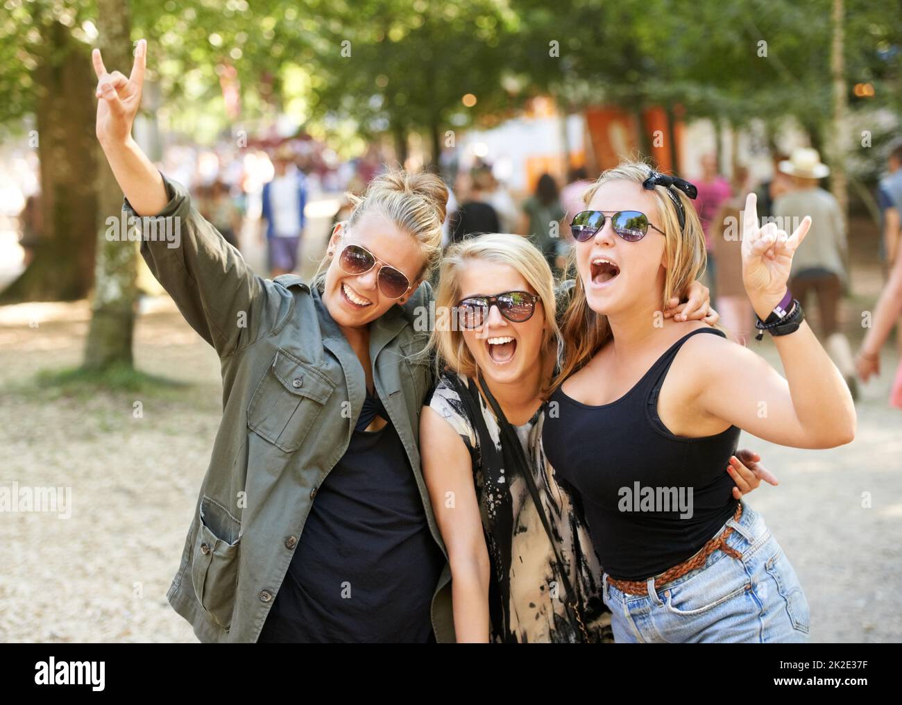 Dandogli avvisatori acustici. Tre amiche che festeggiano un festival musicale all'aperto. Foto Stock