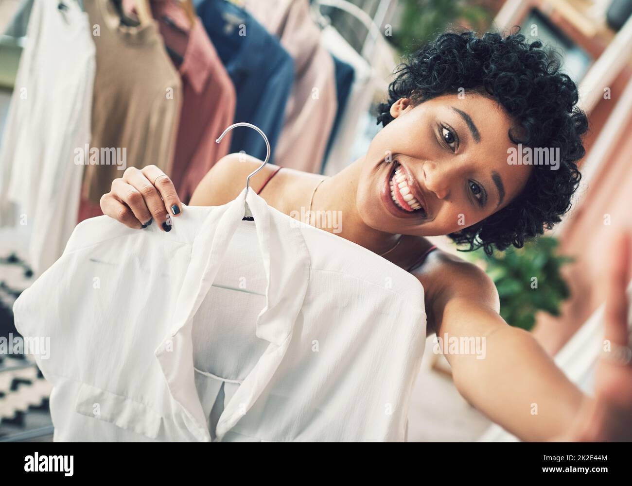 Ogni fashionista sa che una camicia bianca è un capo indispensabile per il guardaroba. Scatto ritagliato di una donna che tiene una camicia verso la fotocamera. Foto Stock