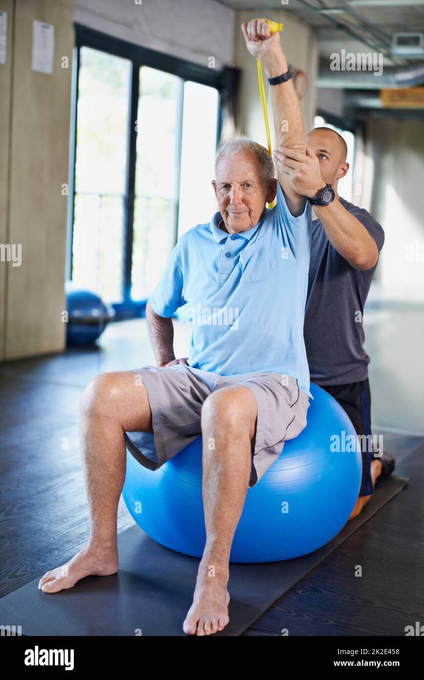 Stretching e rafforzamento. Un allenatore che aiuta un uomo anziano con il fitness. Foto Stock