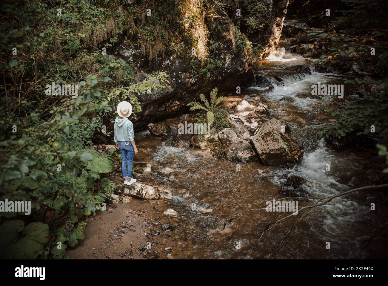 Giovane escursione turistica sul fiume di montagna godendo del paesaggio, camminando lungo le rocce. Foto Stock