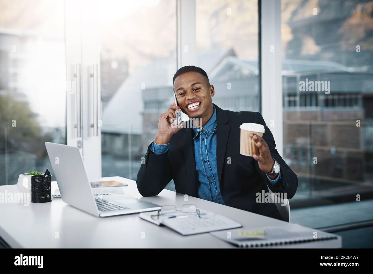 Conosce tutto sul business. Scatto di un bel giovane uomo d'affari che parla su un cellulare mentre lavora in un ufficio. Foto Stock