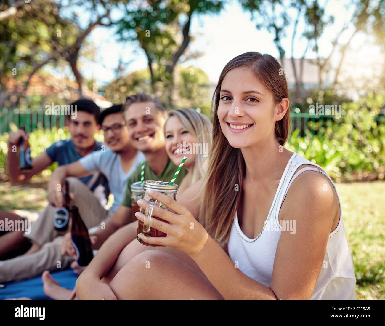 Avere il miglior tempo di sempre. Ritratto corto di una giovane donna attraente godendo un po' di bevande con gli amici all'aperto nel sole estivo. Foto Stock