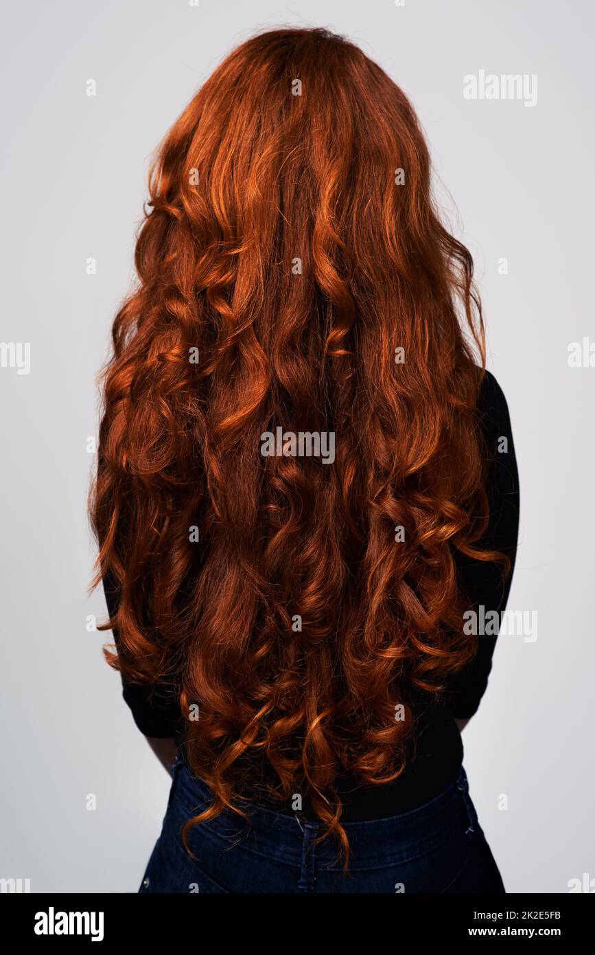 Crescere a lungo, crescere forte. Studio girato di una giovane donna con bei capelli rossi in posa su uno sfondo grigio. Foto Stock