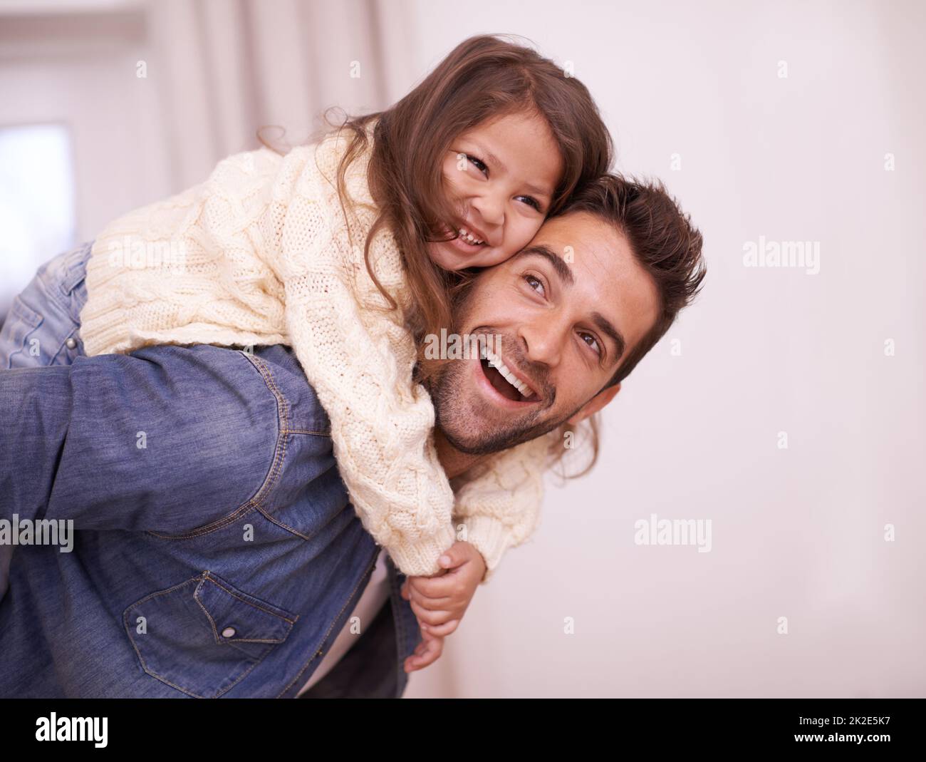 Divertimento con papà. Sparato di un padre che dà a sua figlia un giro di piggyback a casa. Foto Stock